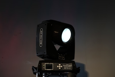 Close-up of a professional spotlight casting a sharp beam on a dark stage.