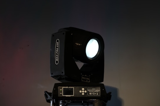 A professional stage spotlight with a black casing is positioned against a dark background. The spotlight emits a bright, focused beam of light. The model name 'MAX-PRO 230' is visible on the side.