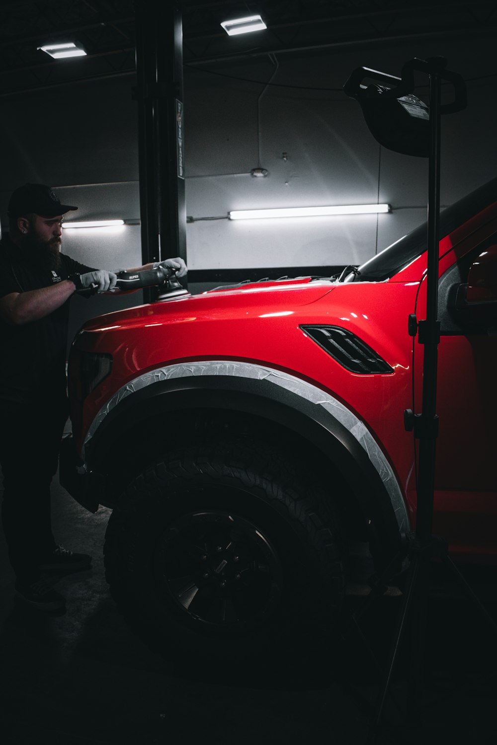 man in white t-shirt standing beside red car