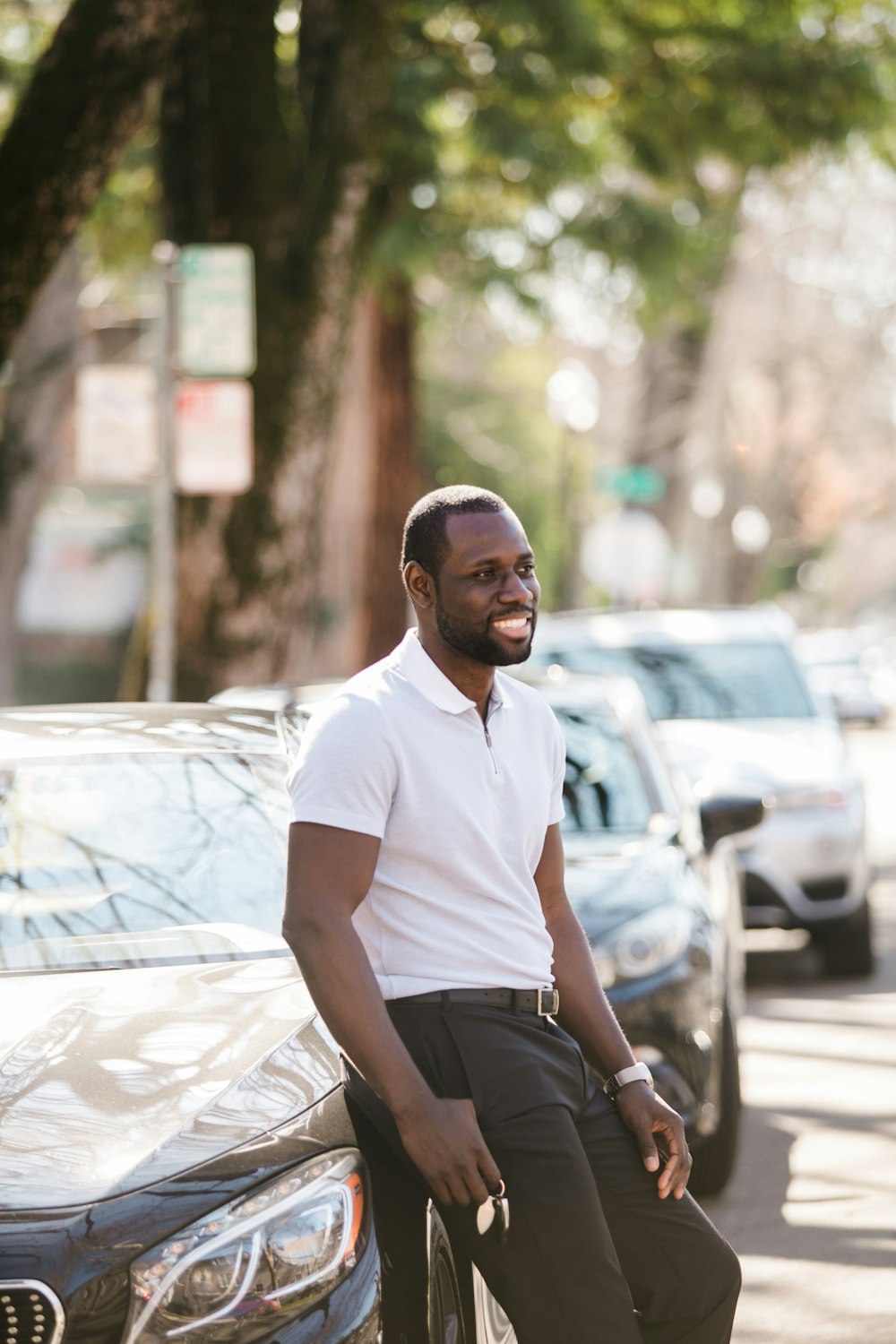 homme en polo blanc assis sur une voiture blanche