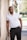man in white polo shirt and black pants standing beside white wall during daytime