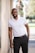 man in white polo shirt and black pants standing beside white wall during daytime
