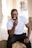 man in white crew neck t-shirt and black pants sitting on white concrete wall during