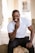 man in white crew neck t-shirt and black pants sitting on white concrete wall during