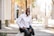 man in white dress shirt and black pants sitting on the sidewalk during daytime