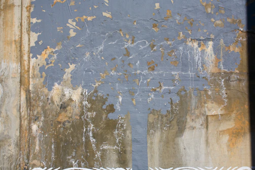 A cracked concrete wall with faded stripes and dripping rust stains under slow-moving fog.