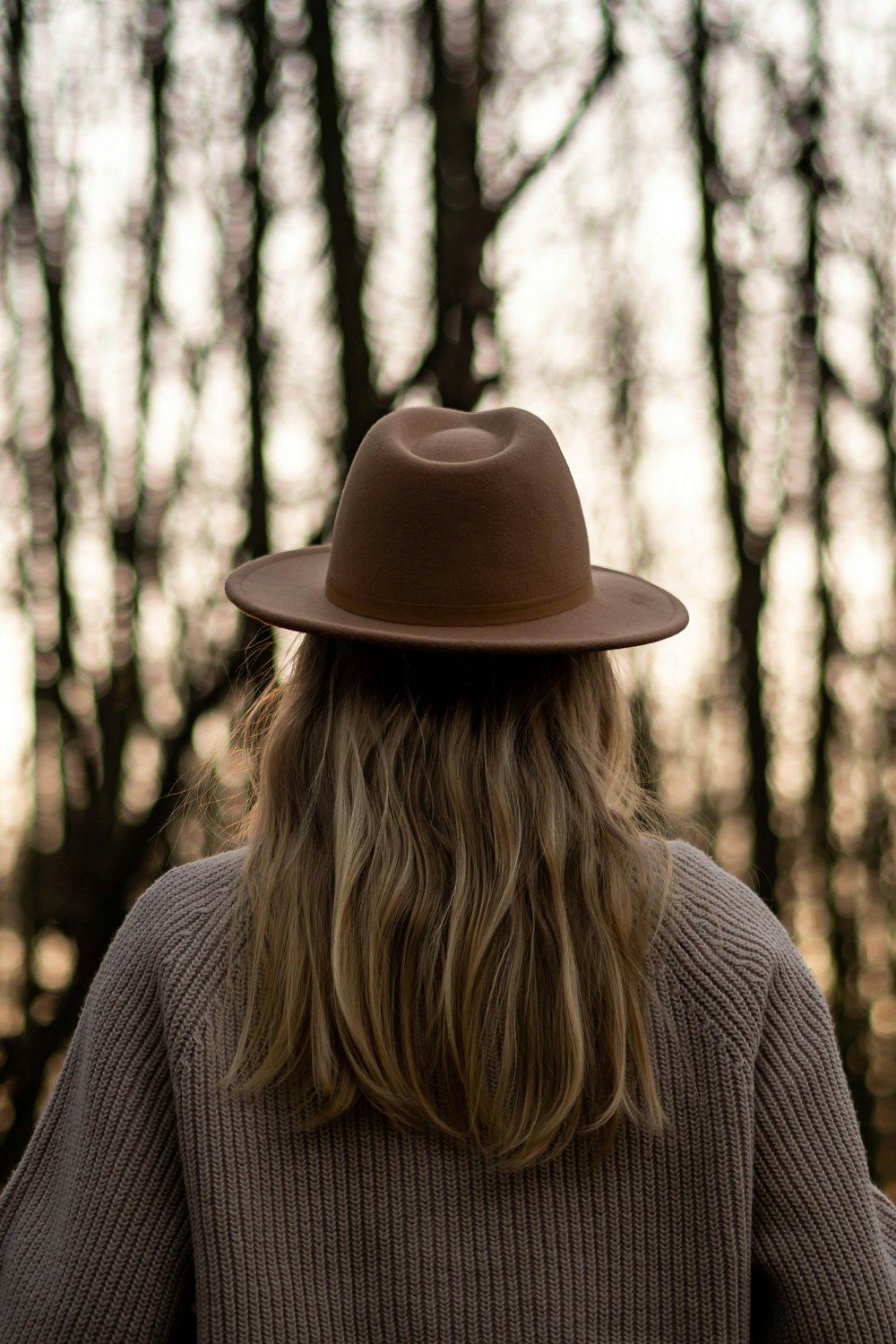woman in gray sweater wearing brown fedora hat