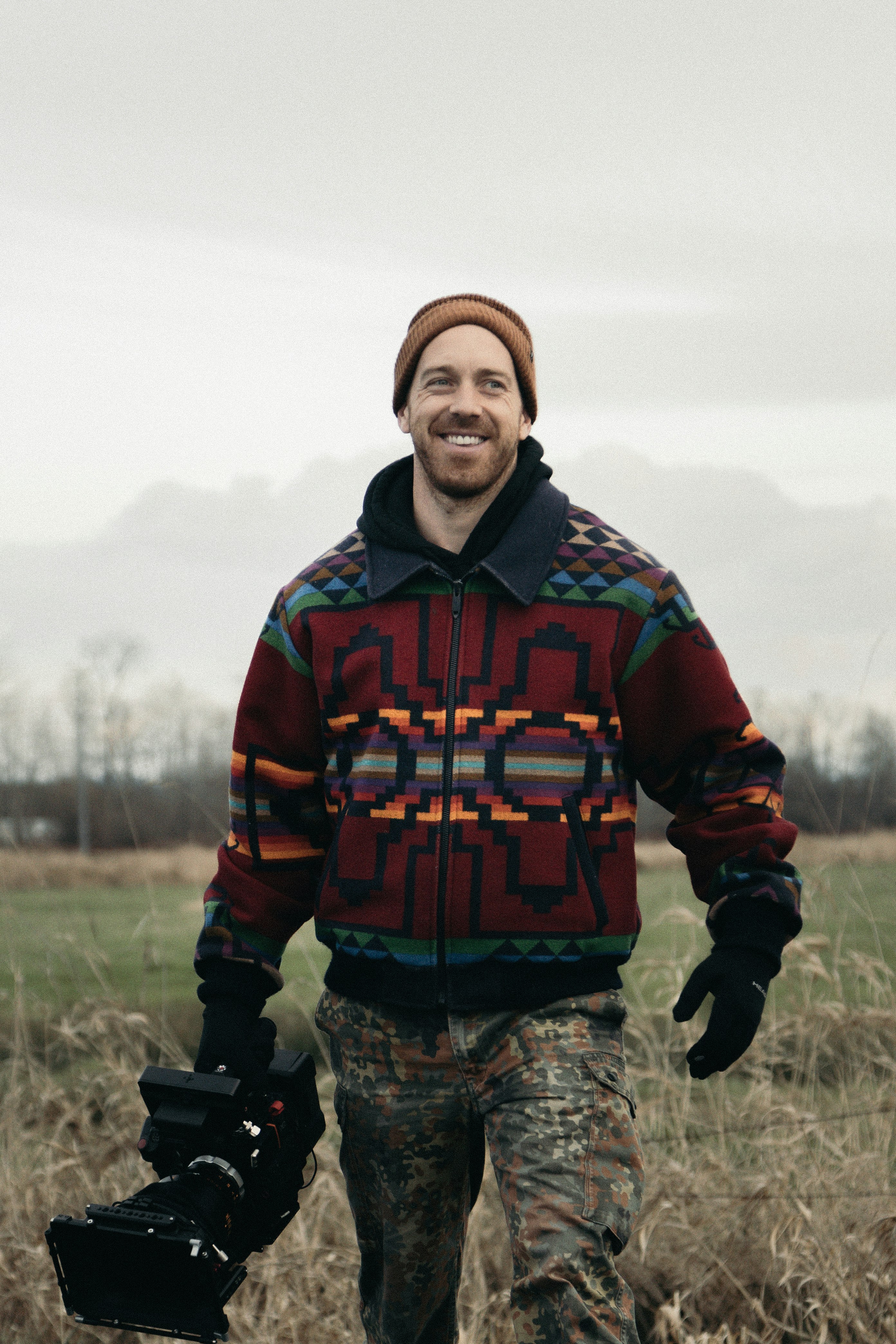 man in red and blue zip up jacket standing on brown grass field during daytime