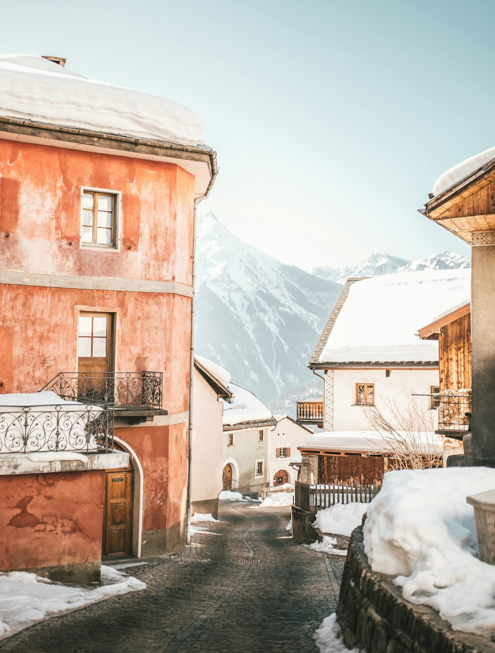 brown concrete building near snow covered mountain during daytime