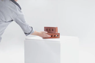 Close-up of skilled hands laying bricks with a vivid red trowel in focus.