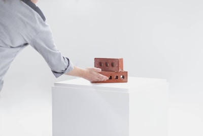 Close-up of a hand laying bricks carefully, symbolizing precision and reliability.