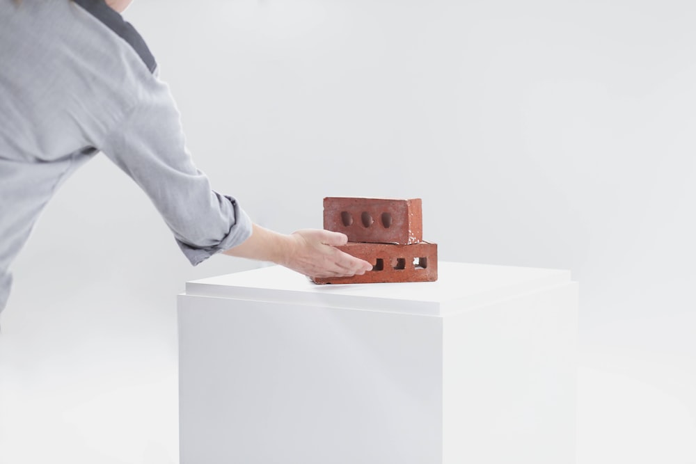 person holding brown wooden cube