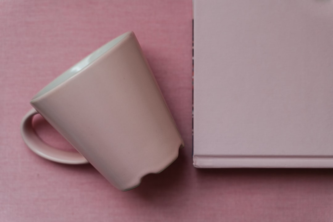 white ceramic mug on pink textile