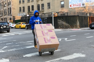 man in blue hoodie holding brown cardboard box
