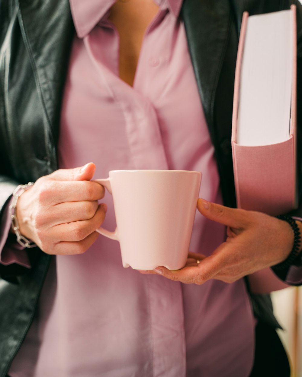 homem no blazer preto segurando caneca de cerâmica branca