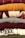 A stack of neatly folded knitted sweaters with various textures and patterns, showing a range of colors from deep red and mustard yellow to gray, burgundy, and patterned white and black. The fibers and knitting patterns are clearly visible, emphasizing the cozy and warm nature of the garments.