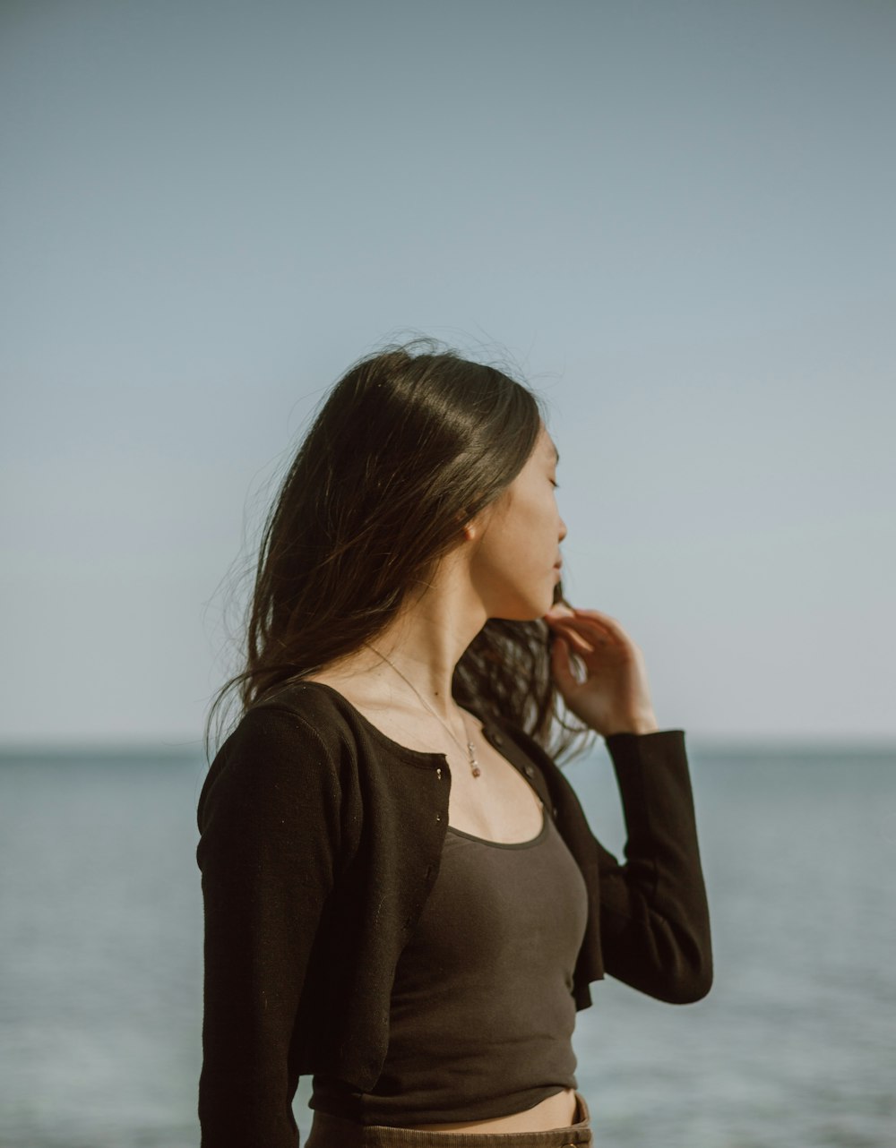 woman in black long sleeve shirt standing near body of water during daytime