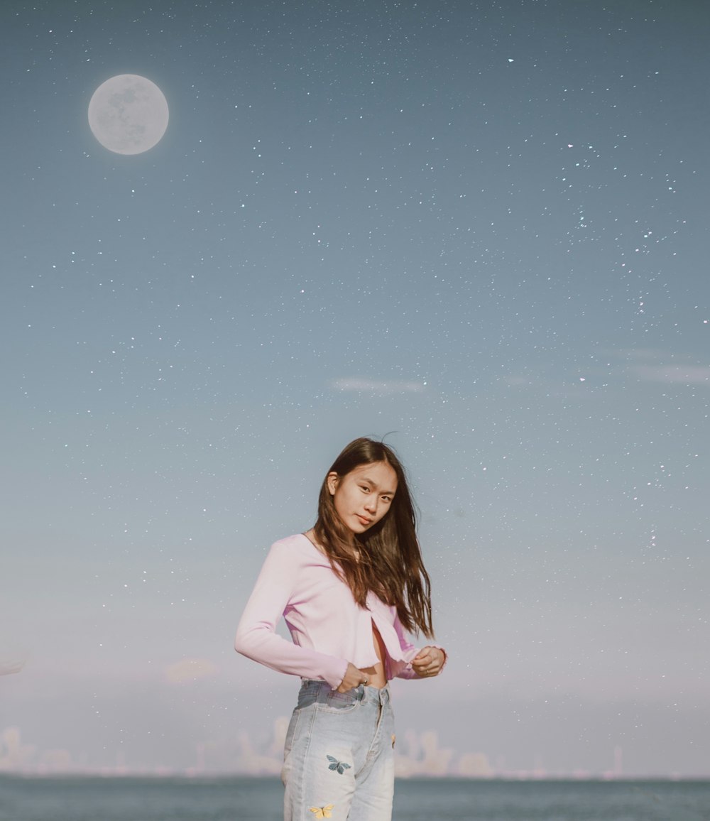 woman in white long sleeve shirt and blue denim jeans standing under full moon