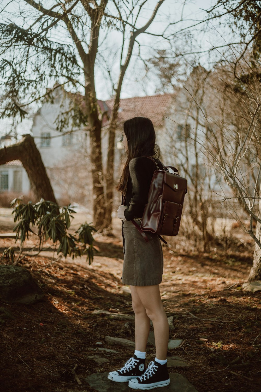 woman in black dress carrying black leather sling bag