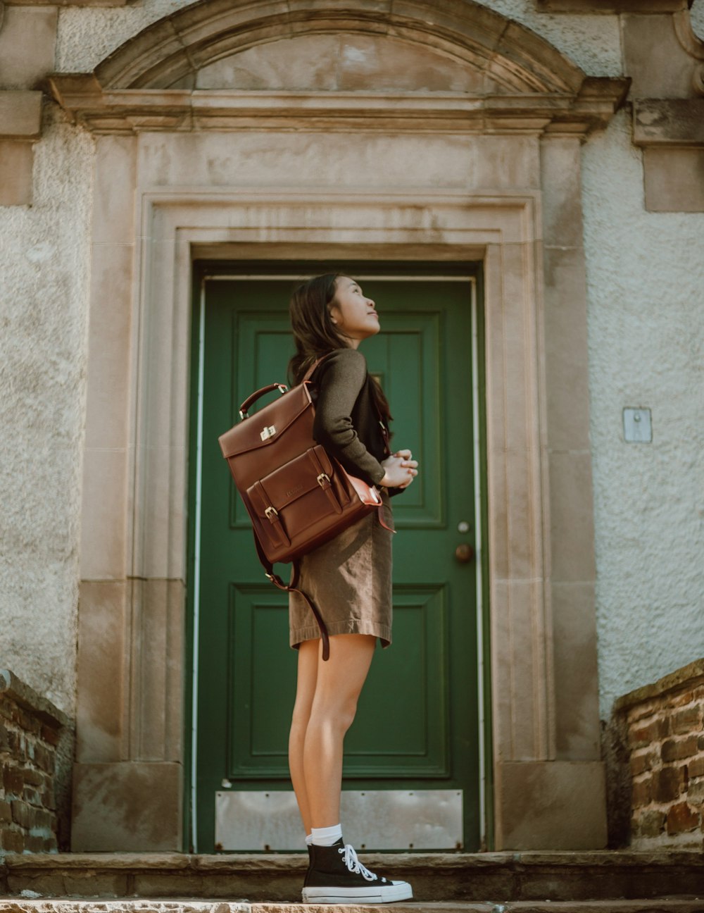 woman in brown long sleeve dress holding brown leather handbag