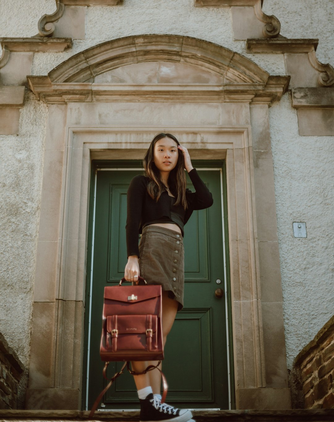 woman in black long sleeve shirt and pink skirt standing beside brown wooden door