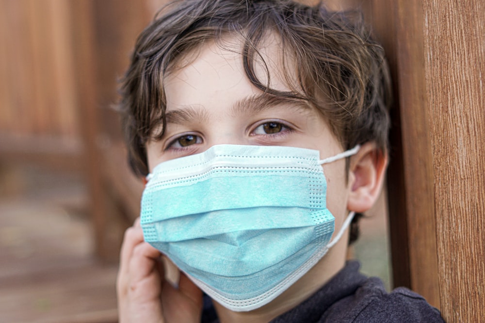 boy covering his face with white and blue face mask