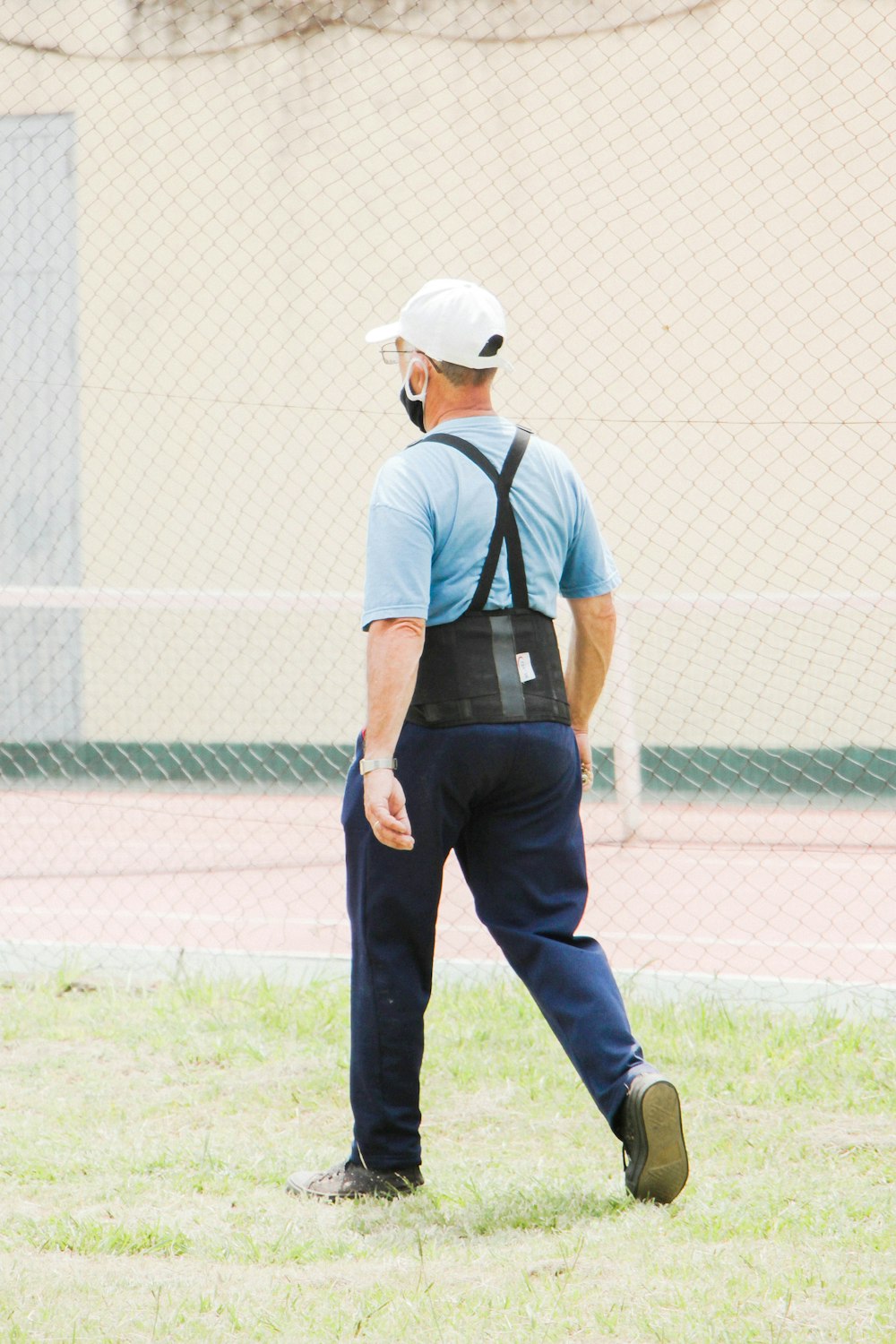 man in white t-shirt and blue denim jeans standing on green grass field during daytime