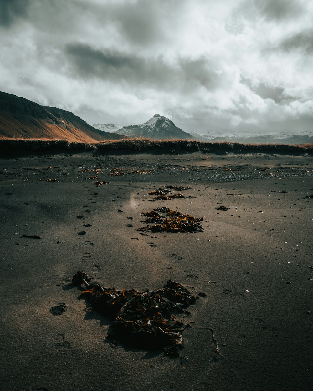 brown sand near mountain under white clouds during daytime