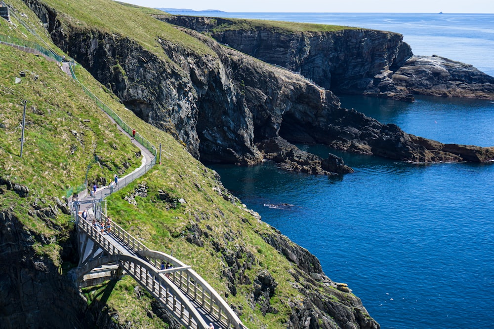 white wooden bridge on green mountain near blue sea during daytime