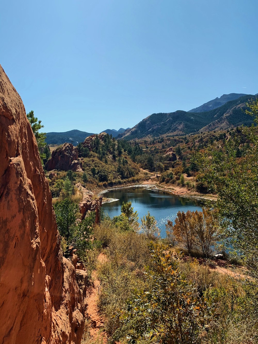 brown rocky mountain beside blue lake under blue sky during daytime