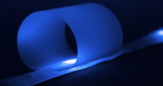A glowing prototype device emitting soft blue light in a dark room.