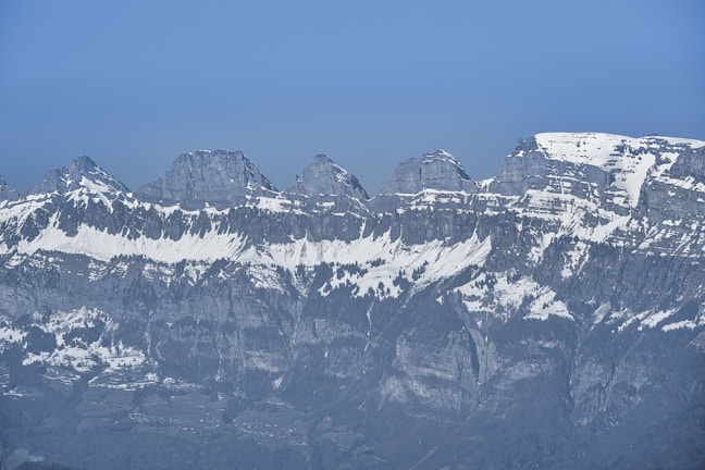 Wide panoramic view of rugged mountain ridges dusted with snow.