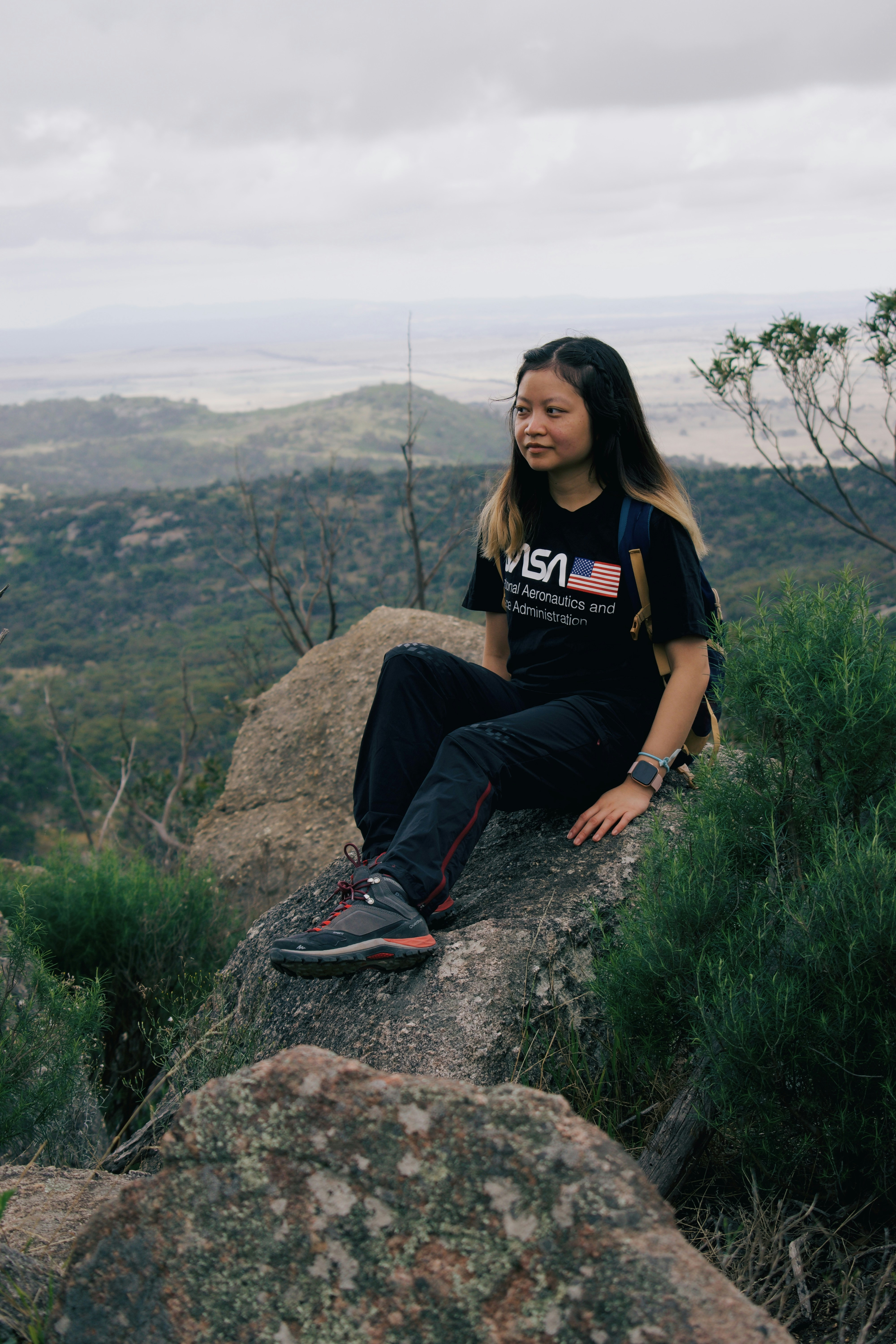 woman in black crew neck t-shirt sitting on rock during daytime