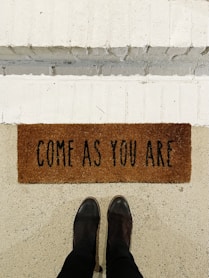 person standing on brown and black welcome printed floor mat