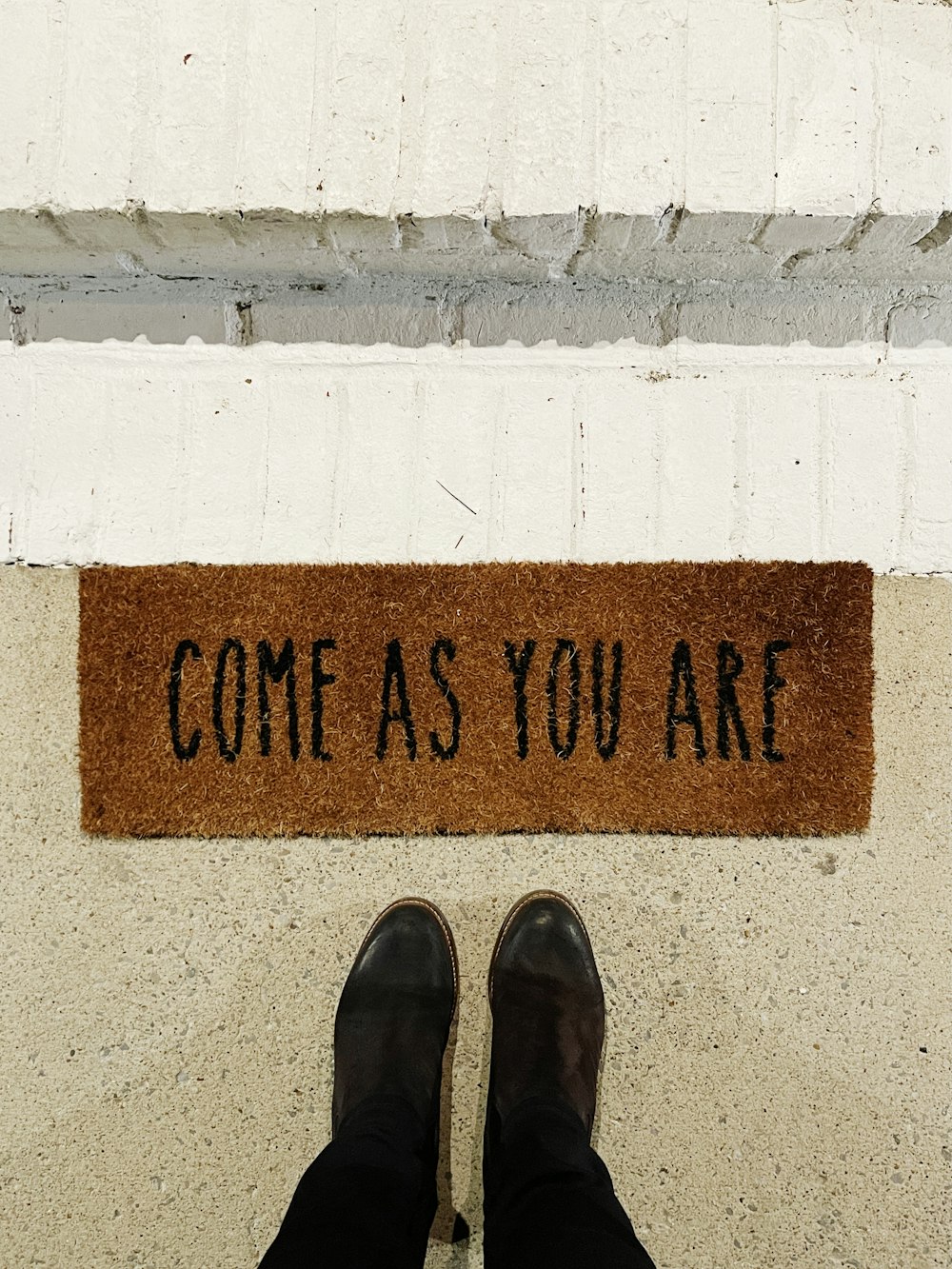 person standing on brown and black welcome printed floor mat