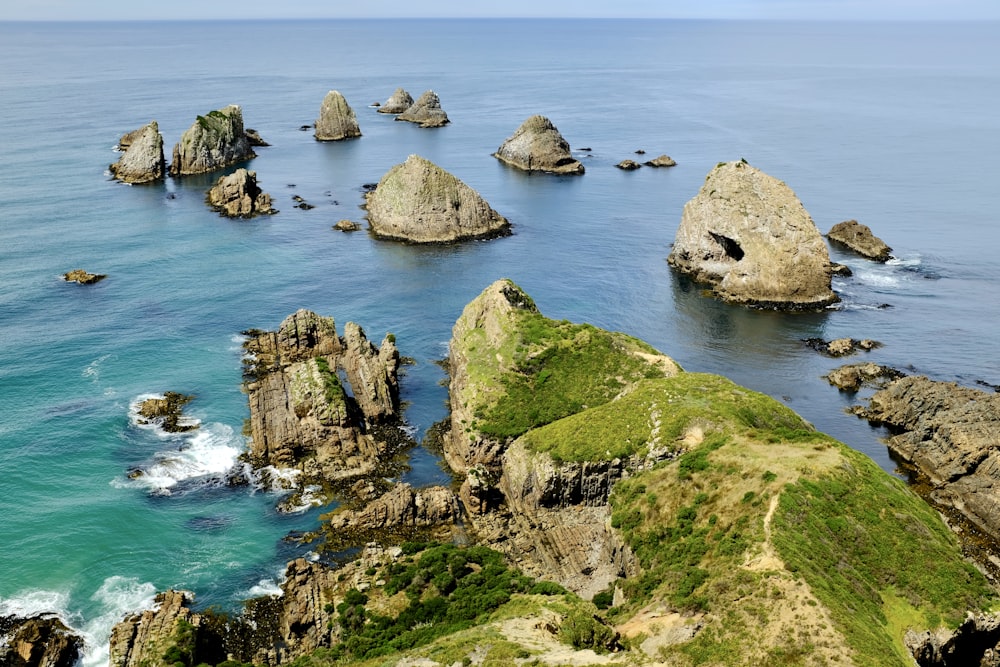 green and brown rock formation on sea during daytime