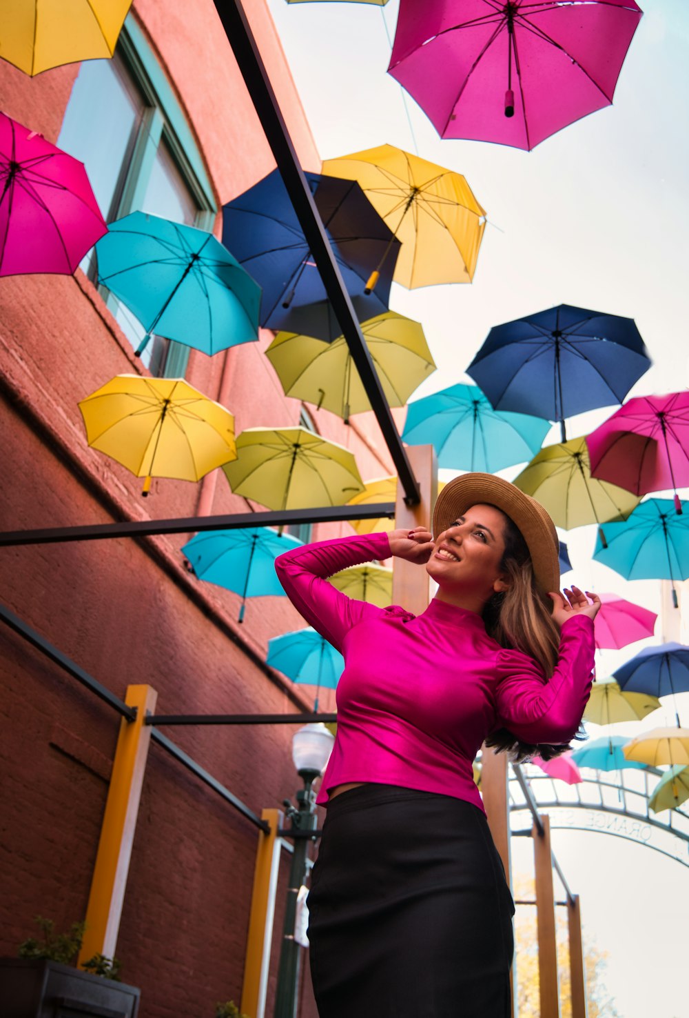 woman in pink long sleeve shirt and blue denim jeans holding umbrella