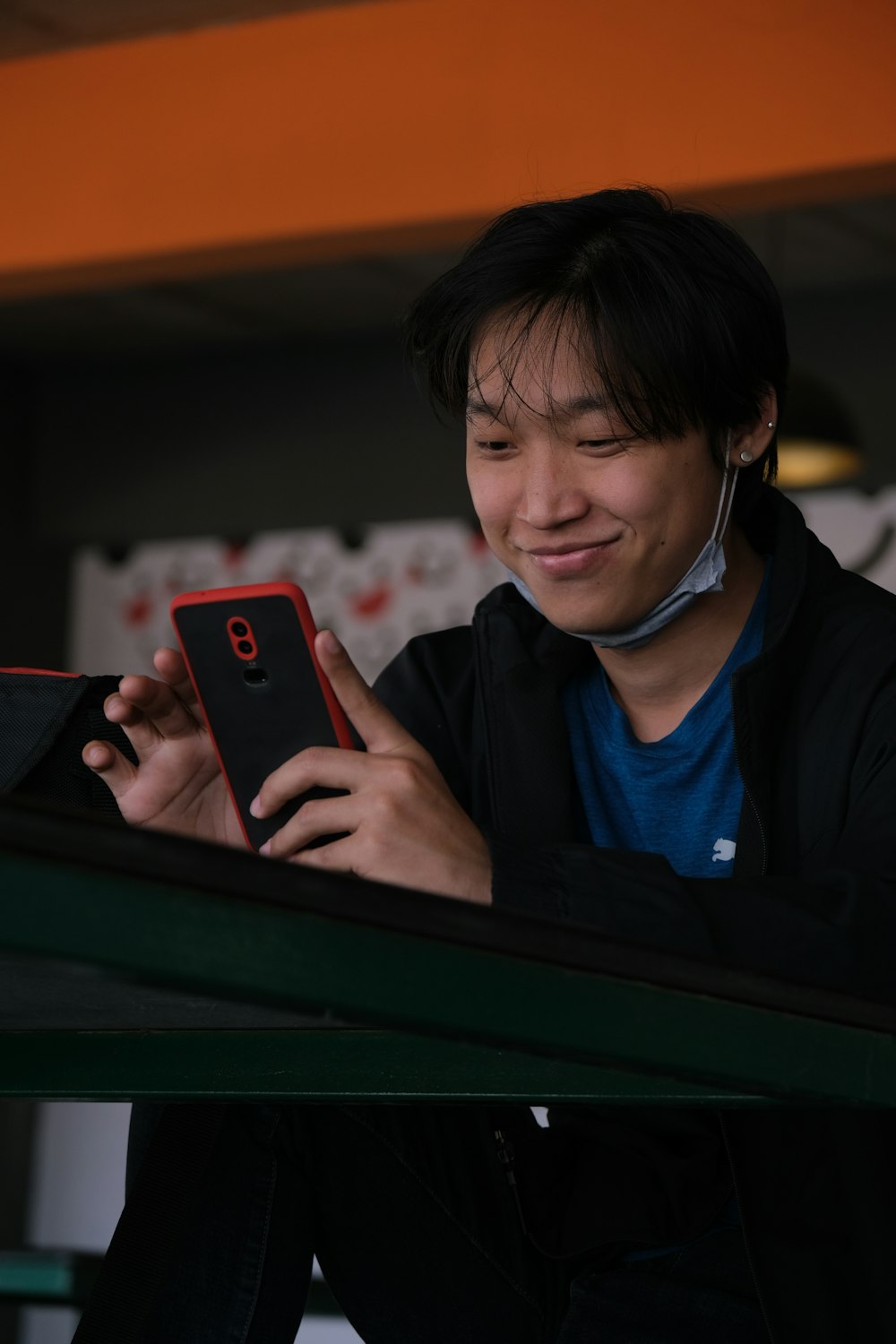 boy in blue and black jacket holding black smartphone