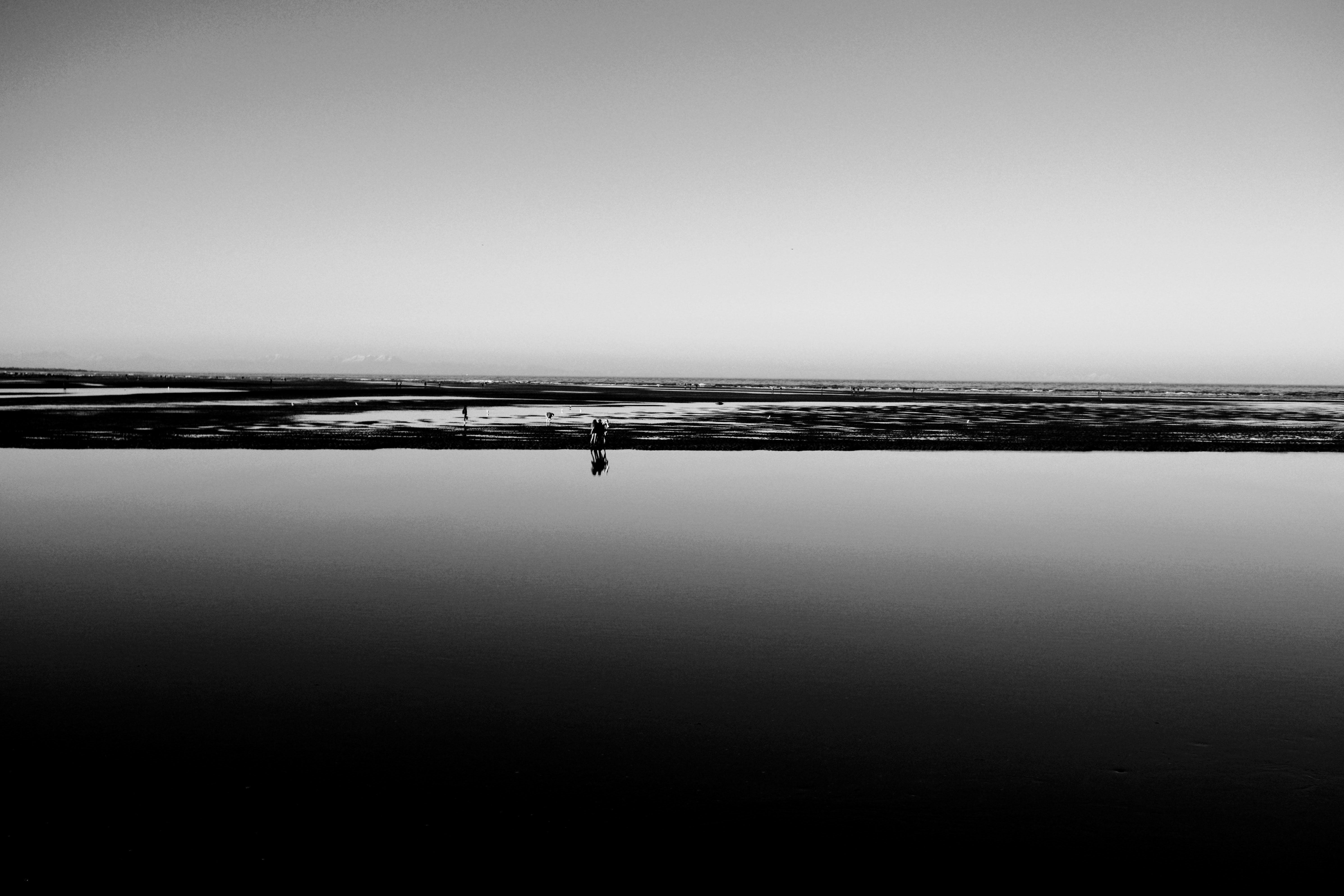 grayscale photo of a person walking on a beach