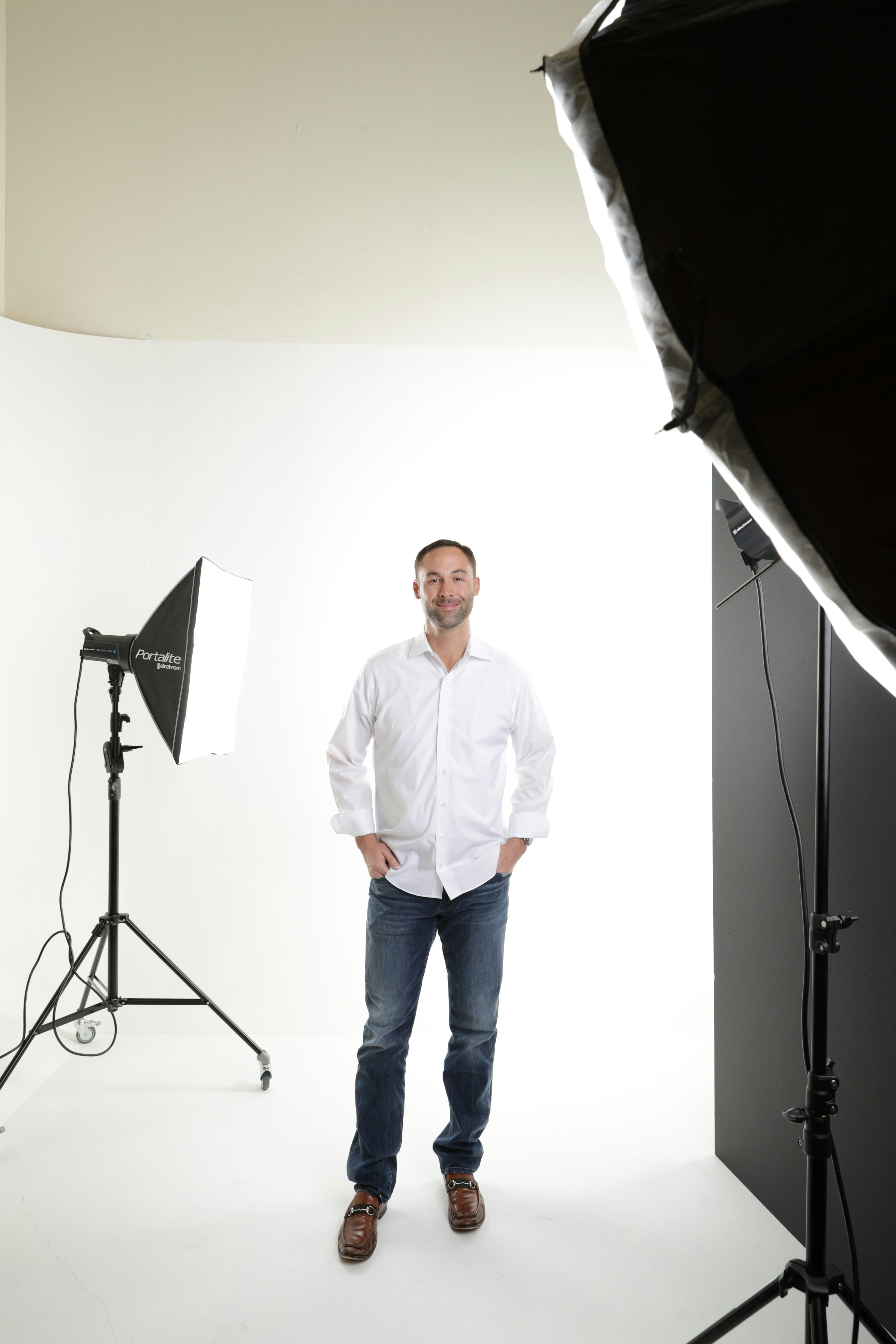 검은 마이크 스탠드 근처에 서 있는 흰색 드레스 셔츠를 입은 남자