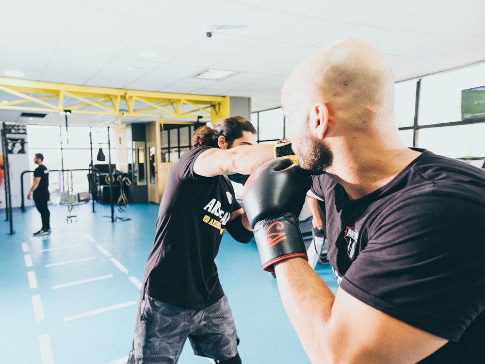 man in black crew neck t-shirt and black shorts wearing black boxing gloves