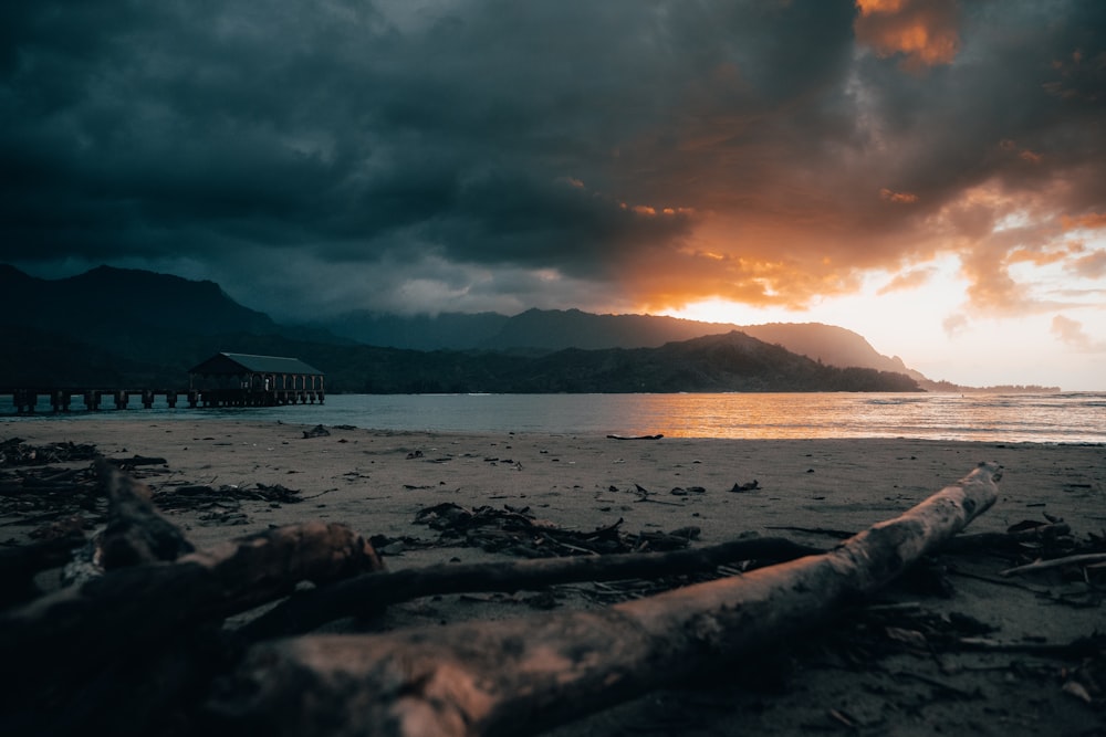 silhouette of mountain near body of water during sunset