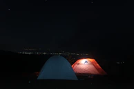 An outdoor night scene showing bell tents glowing warmly under a starry sky, perfect for a sleepover.
