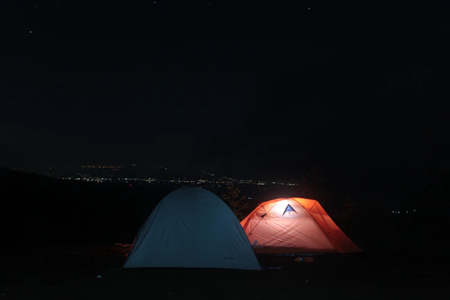 A minimalist campsite setup under a starry night sky, glowing softly.