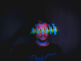 man in black crew neck shirt with blue and white light on his face