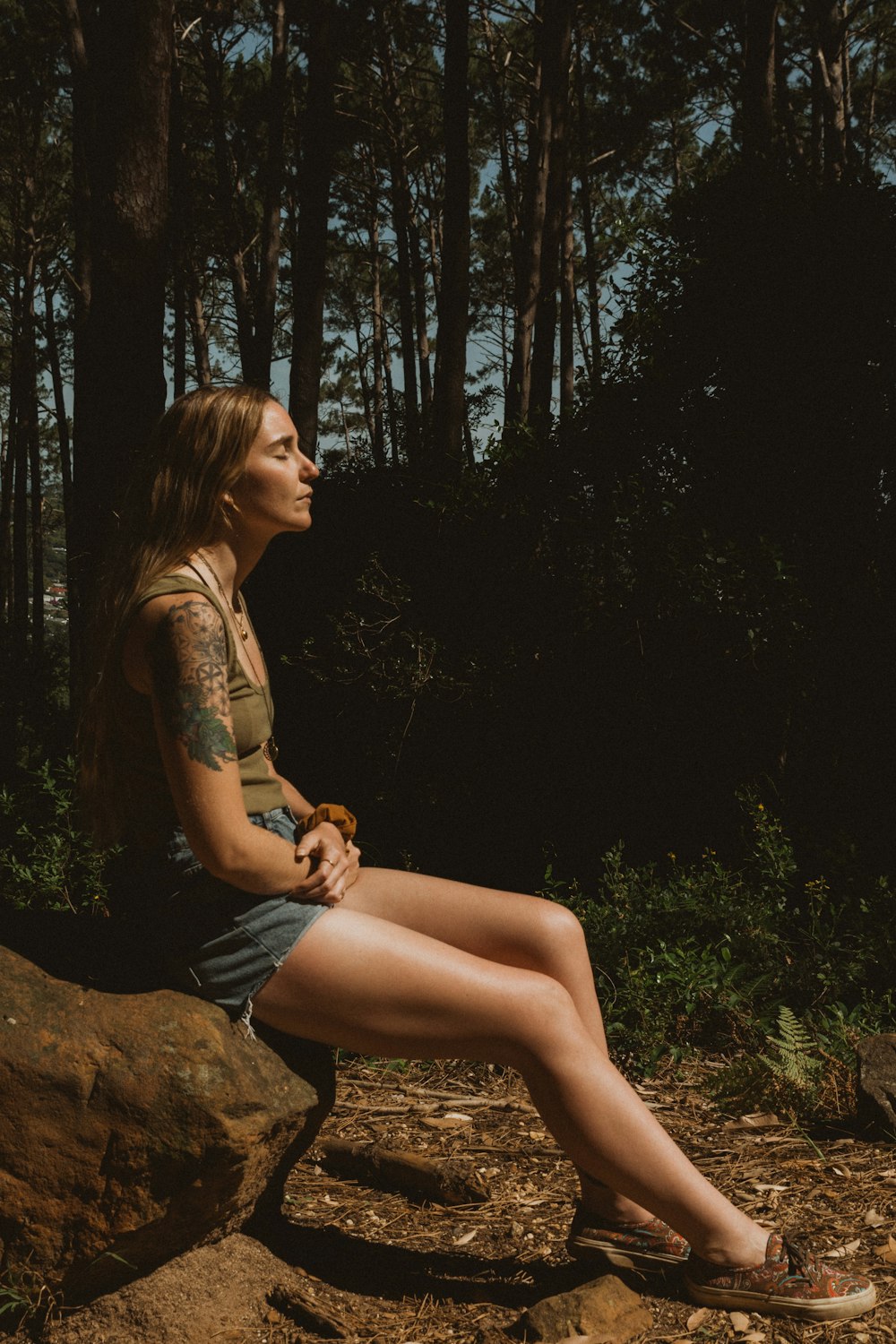 woman in brown floral shirt sitting on brown rock