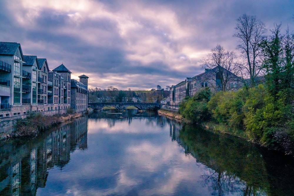 brown and white concrete building beside river under cloudy sky during daytime