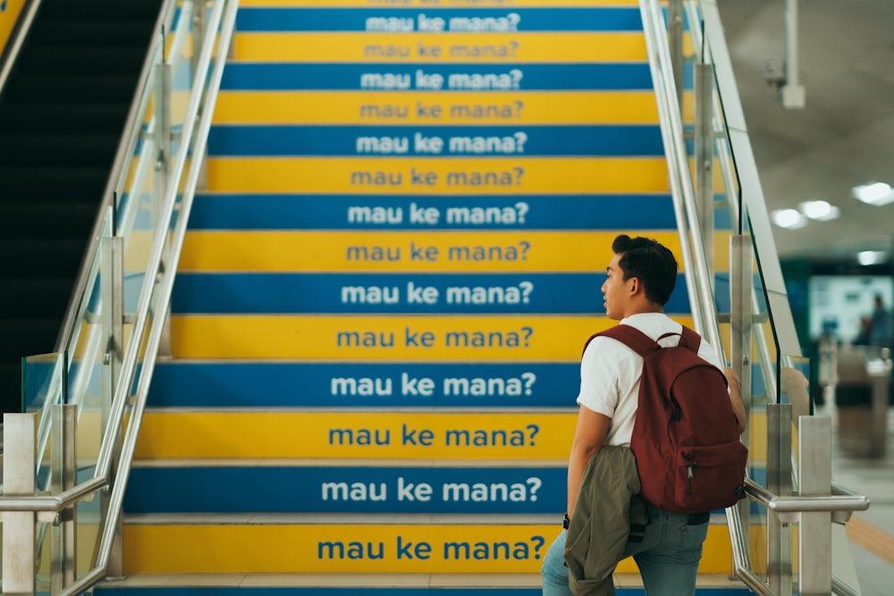 man in red and white polo shirt and blue denim jeans walking on yellow and blue