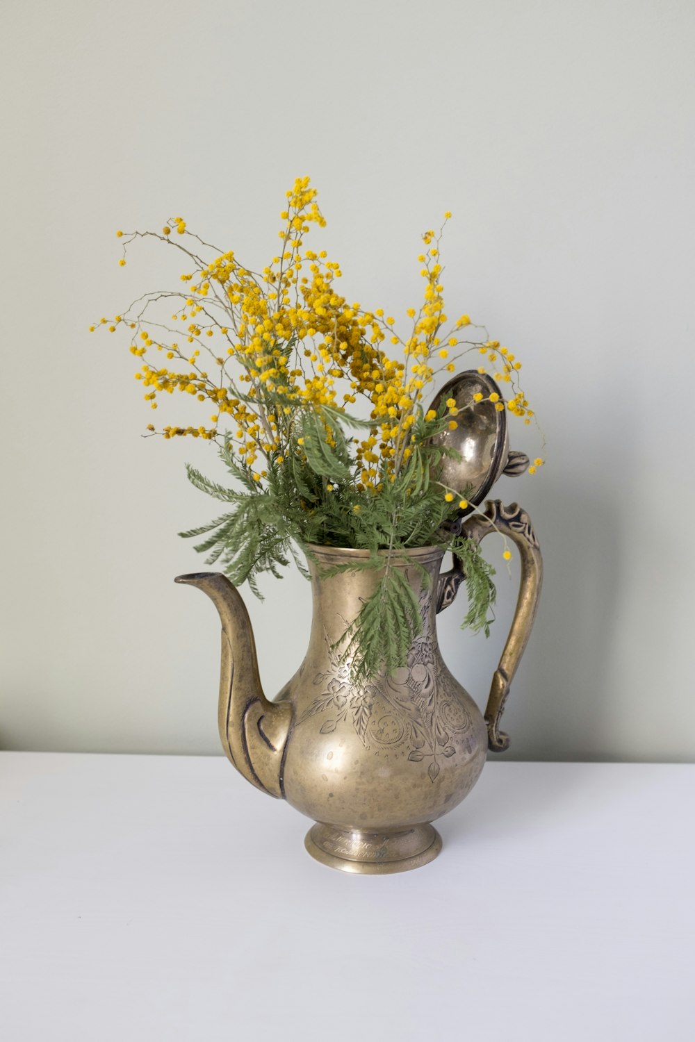 yellow flowers in green ceramic vase