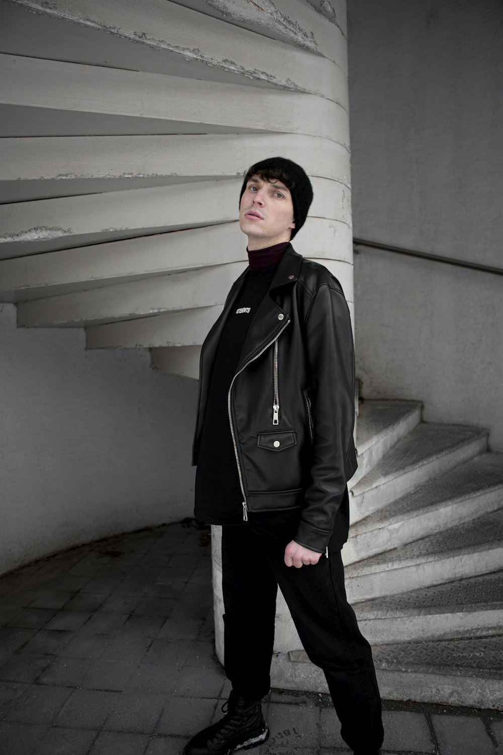 mulher no casaco preto de pé nas escadas de concreto cinzentas